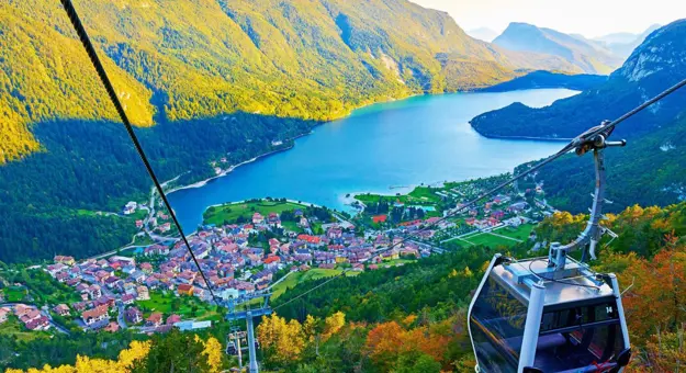 High angle view of the village of Molveno and Lake Molveno in Italy with a cable car in the forefront and the Dolomites in the background