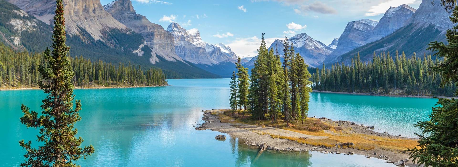 Scenic view of Spirit Island on Maligne Lake in Jasper National Park, Canada, surrounded by turquoise water, pine trees, and snow-capped mountains
