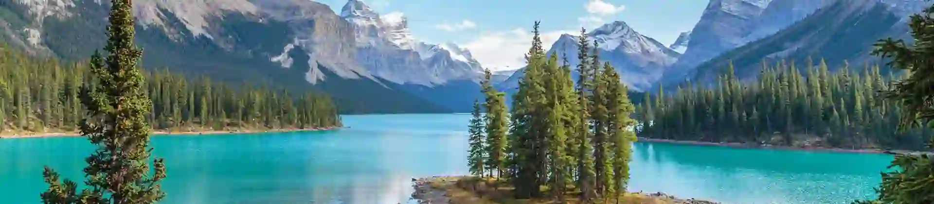 Scenic view of Spirit Island on Maligne Lake in Jasper National Park, Canada, surrounded by turquoise water, pine trees, and snow-capped mountains