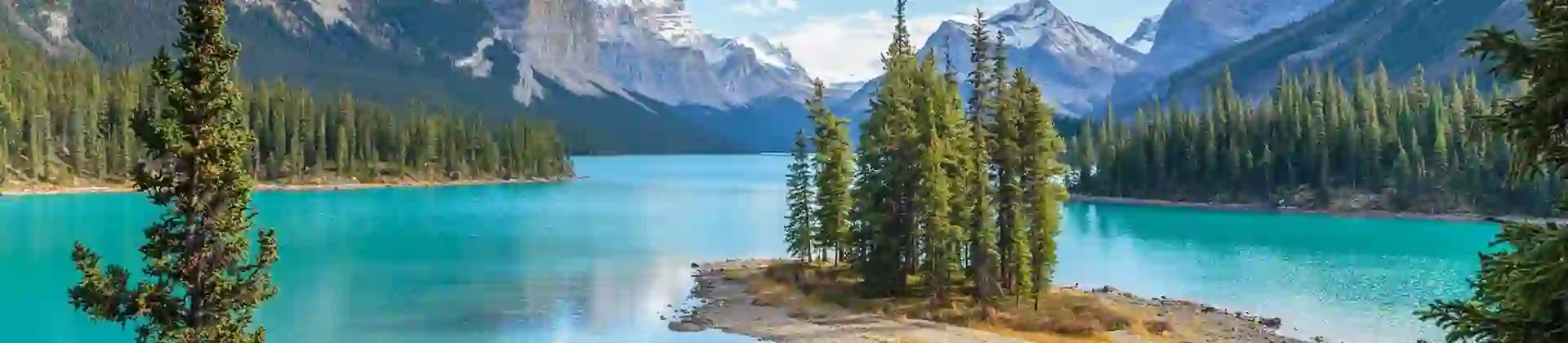 Scenic view of Spirit Island on Maligne Lake in Jasper National Park, Canada, surrounded by turquoise water, pine trees, and snow-capped mountains