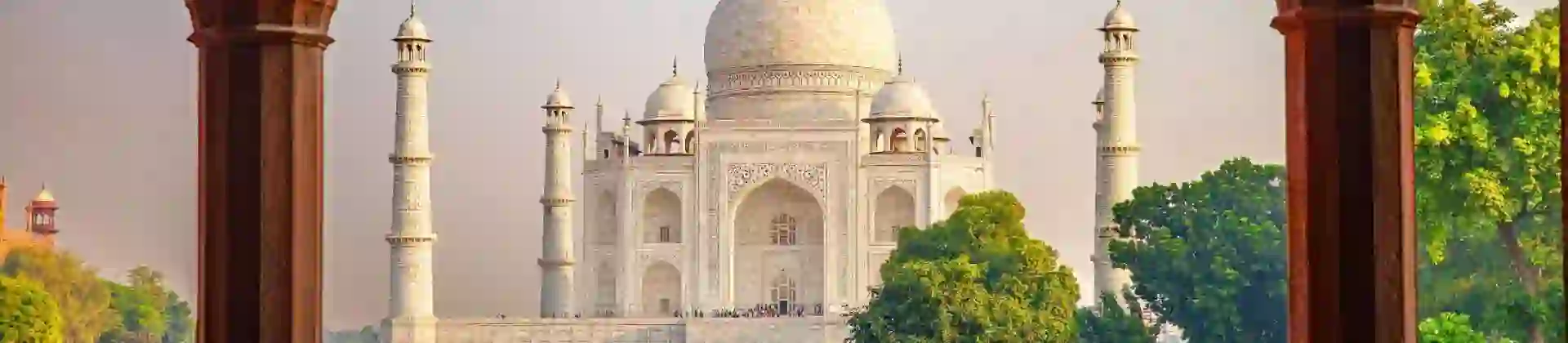 The Taj Mahal framed by an ornate archway, with green gardens in the foreground
