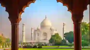 The Taj Mahal framed by an ornate archway, with green gardens in the foreground