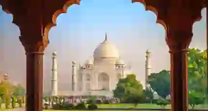 The Taj Mahal framed by an ornate archway, with green gardens in the foreground