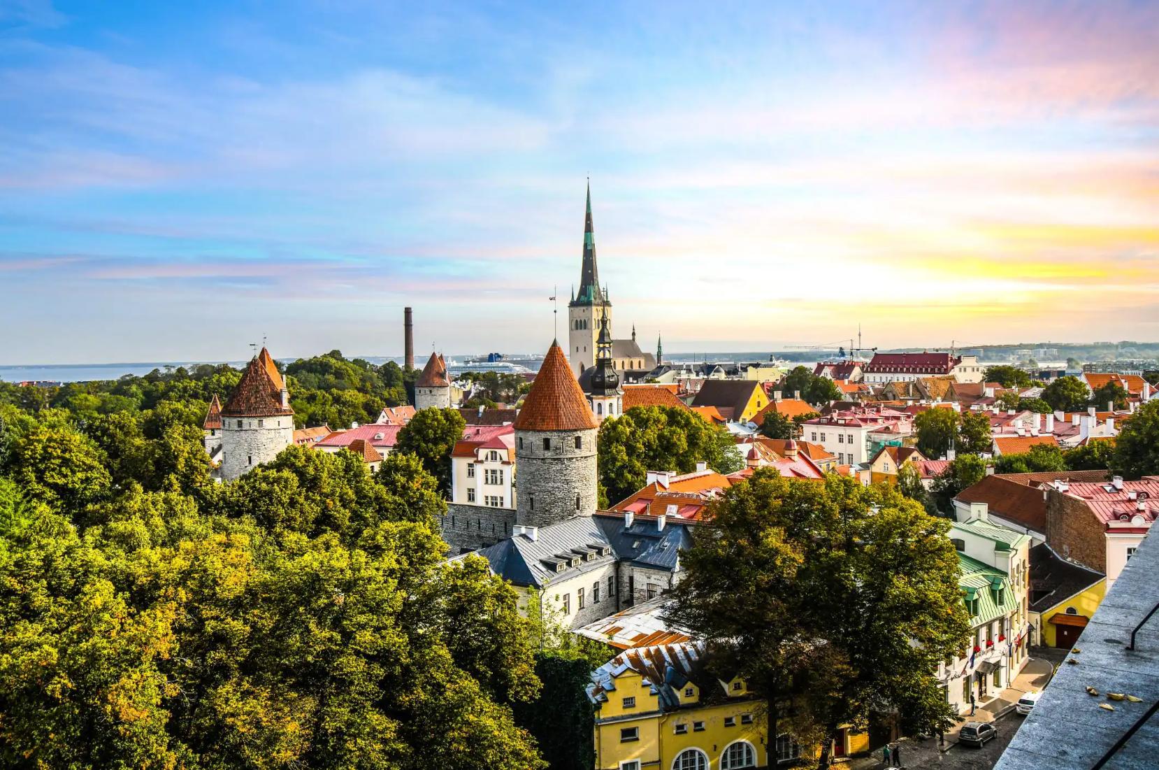 Medieval towers and colourful rooftops in the old town of Tallinn, with a church spire in the background