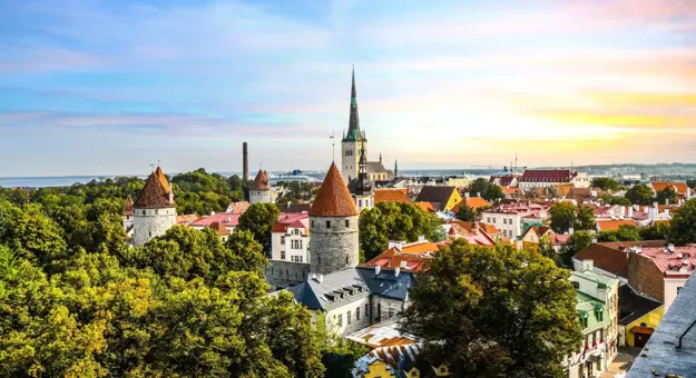Medieval towers and colourful rooftops in the old town of Tallinn, with a church spire in the background