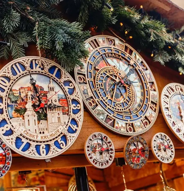 Close up of both big and small antique clocks on the top of a market stall, with artificial leaves and fairy lights along the roof.