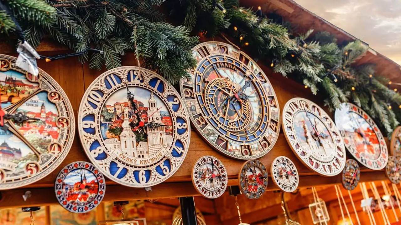 Close up of both big and small antique clocks on the top of a market stall, with artificial leaves and fairy lights along the roof.