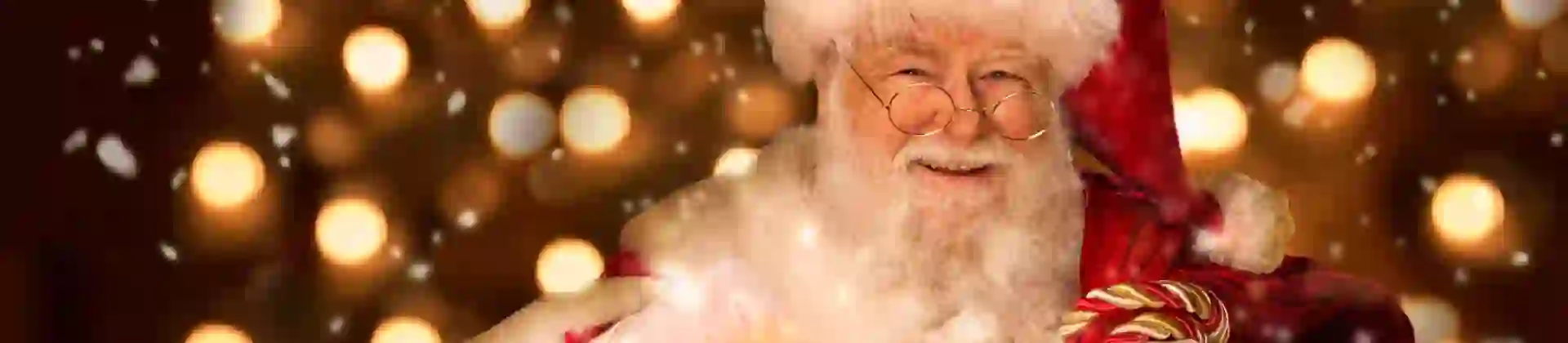 Santa holding a lantern and smiling, with a background of fairy lights