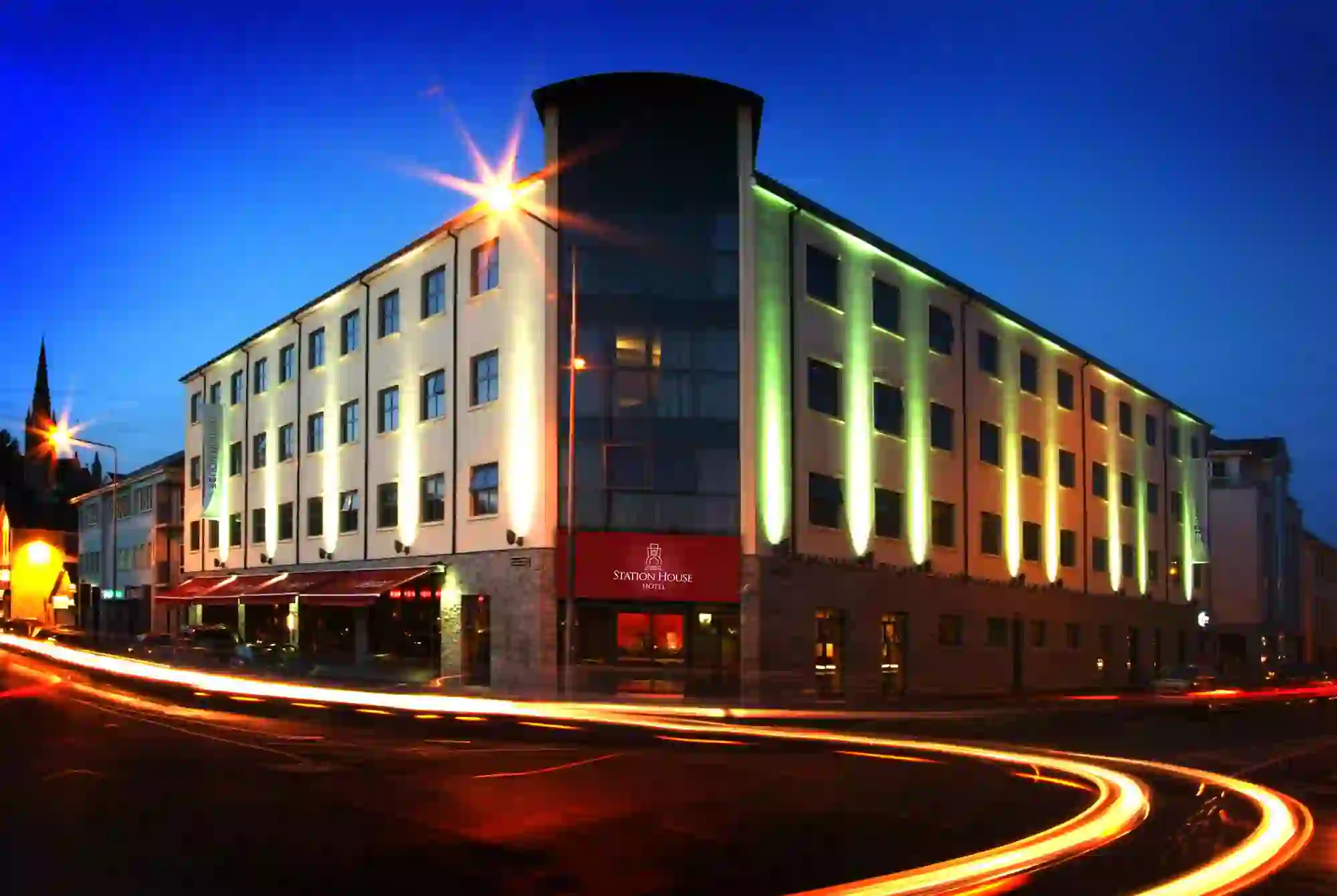 Exterior view of the Station House Hotel, Letterkenny at dusk, with illuminated façade and light trails from passing traffic