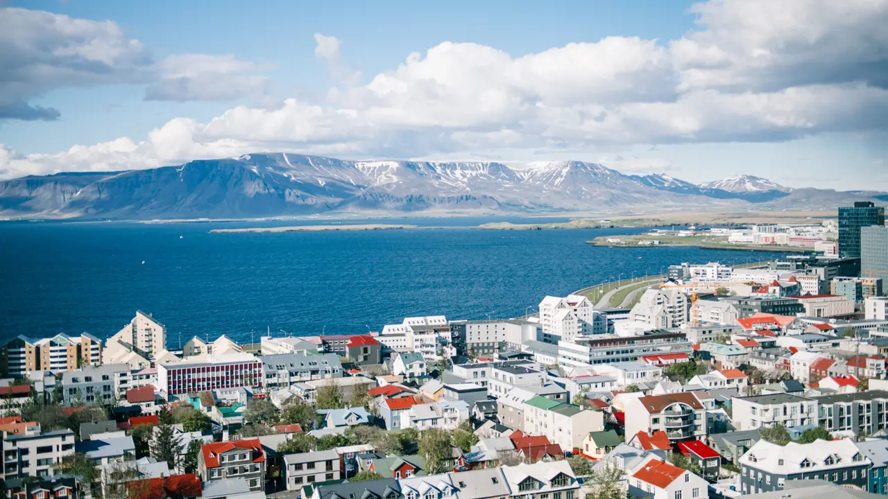 Predominately white houses and buildings of Reykjavik on the waterfront. View of mountains in the distance