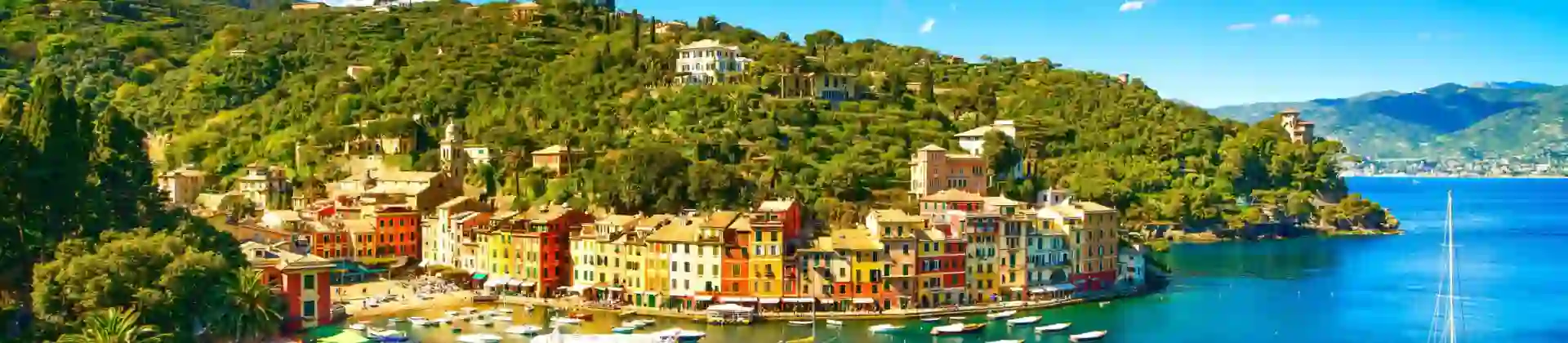 View of a small beach in Portofino, showing boats on the water and buildings on the waterfront