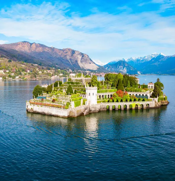 A picturesque view of Isola Bella on Lake Maggiore in Italy, featuring its ornate terraced gardens, elegant architecture and the surrounding mountains reflected in the water