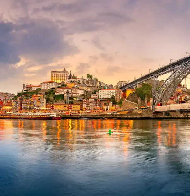 Picturesque view of Porto, Portugal, showing the Dom Luís I Bridge crossing the Douro River, with historic, colourful buildings along the riverbanks
