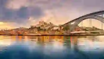 Picturesque view of Porto, Portugal, showing the Dom Luís I Bridge crossing the Douro River, with historic, colourful buildings along the riverbanks