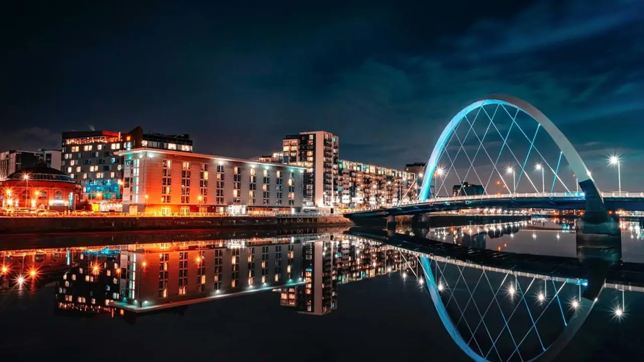 View of the city of Glasgow at night time, with the buildings lit up and The Clyde Arc on the right