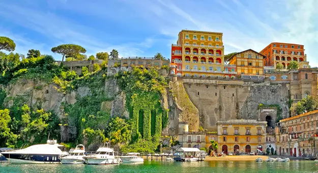 View of Sorrento from the water, with boats in the forefront, stone wall and buildings