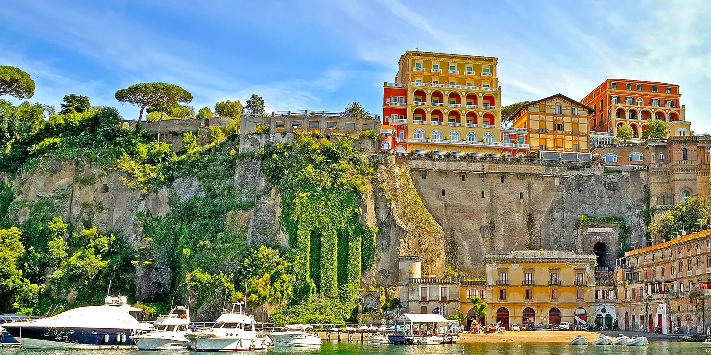 View of Sorrento from the water, with boats in the forefront, stone wall and buildings