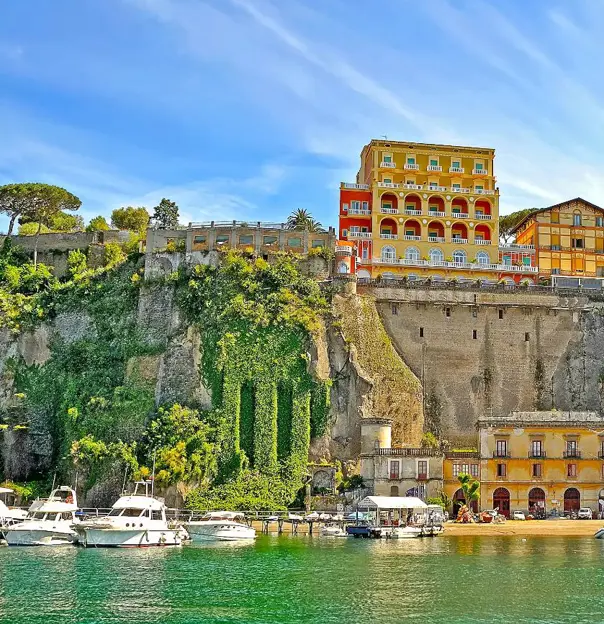 View of Sorrento from the water, with boats in the forefront and hotels and restaurants on the cliff top