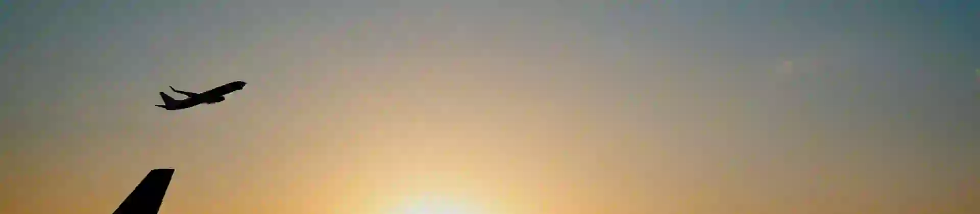 Airplane taking off at sunset over an airport