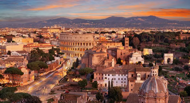 Cityscape of Rome at sunset, showing the Colosseum and St. Peter's Basilica