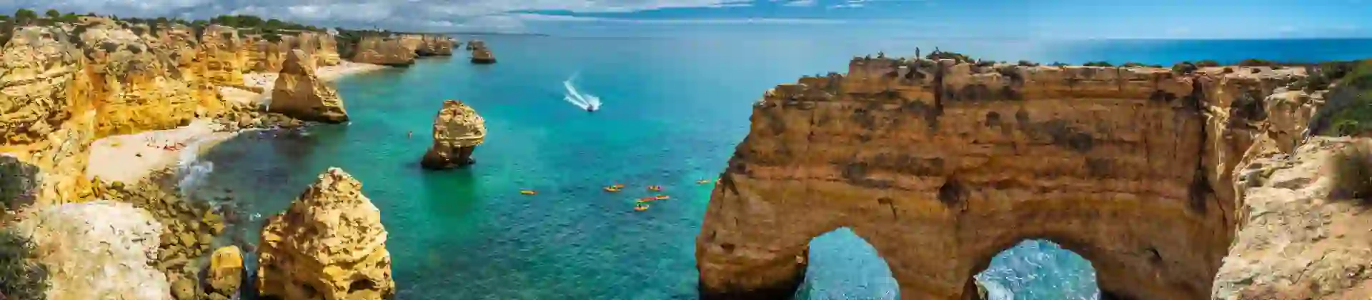 Scenic view of the coves, natural rock arches, and turquoise sea at Praia da Marinha on the Algarve, with rugged cliffs and clear water