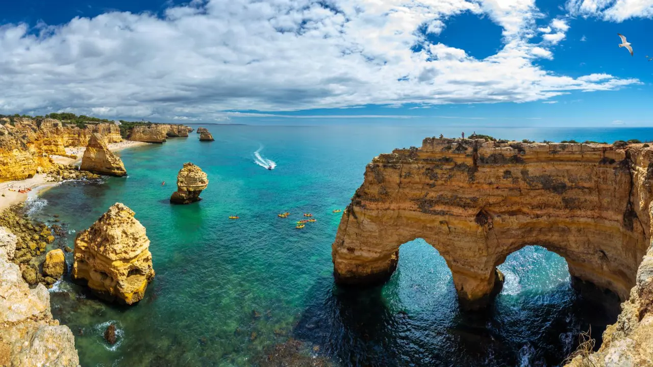 Scenic view of the coves, natural rock arches, and turquoise sea at Praia da Marinha on the Algarve, with rugged cliffs and clear water
