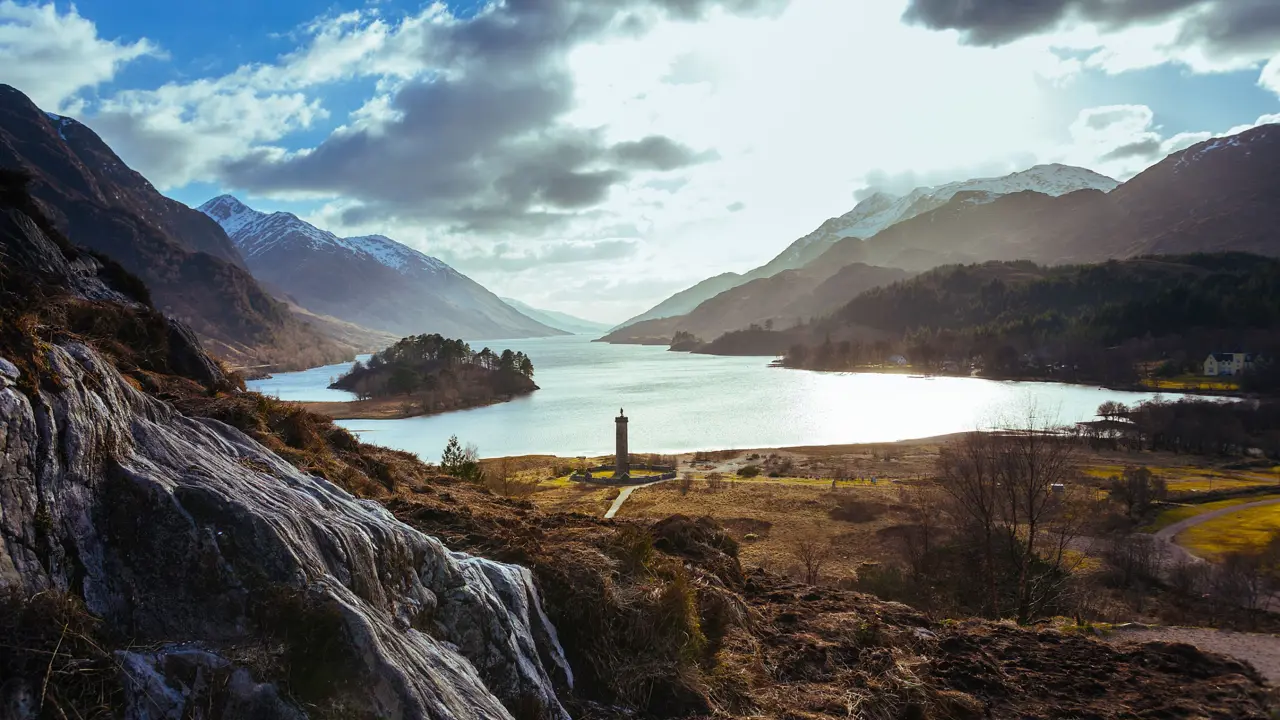 Zoomed out image of Glenfinnan Monument Scotland amongst the highlands with a view of Lock Shiel