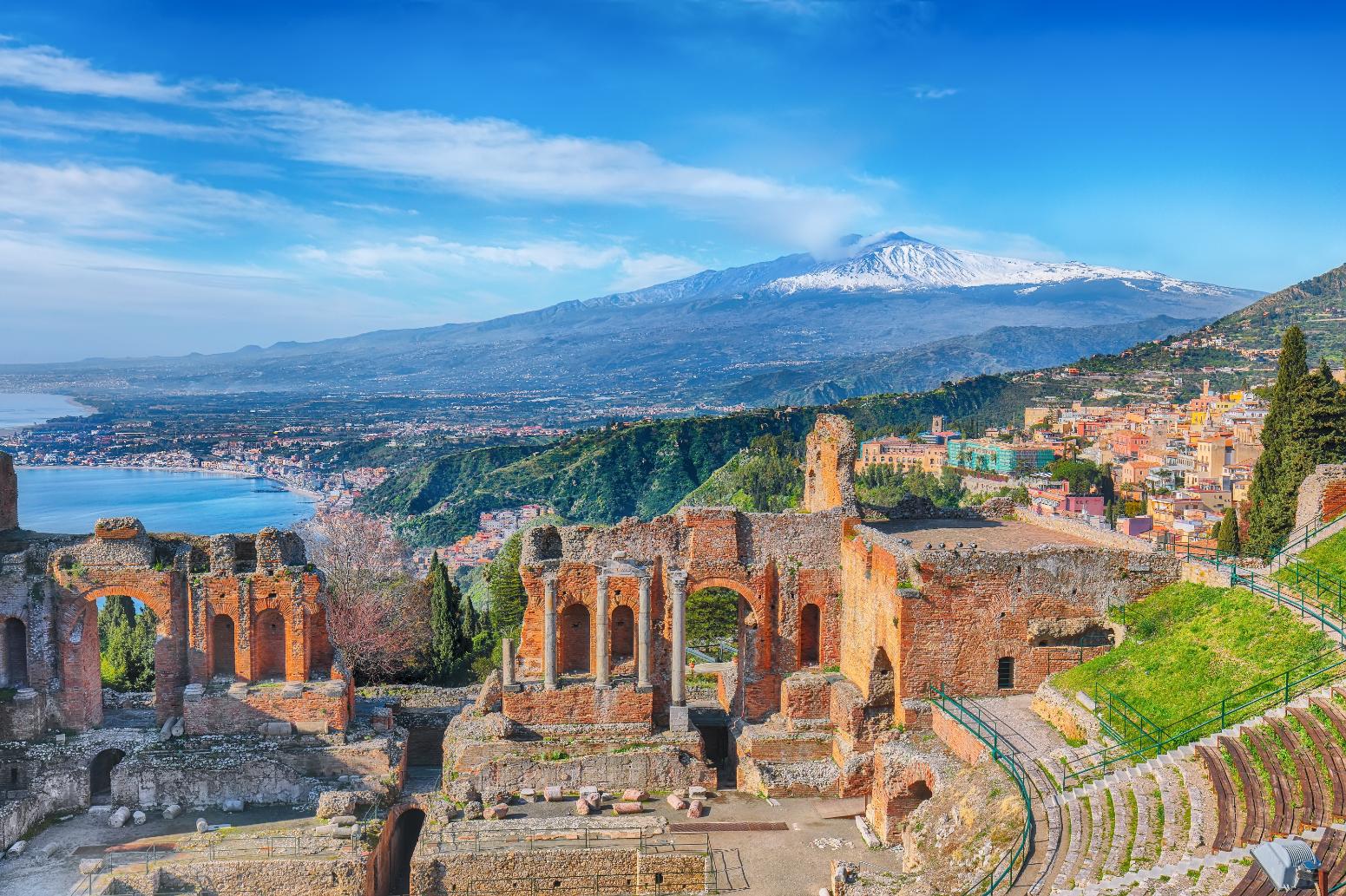 Ruins of ancient Greek theater in Taormina and Etna volcano in the background