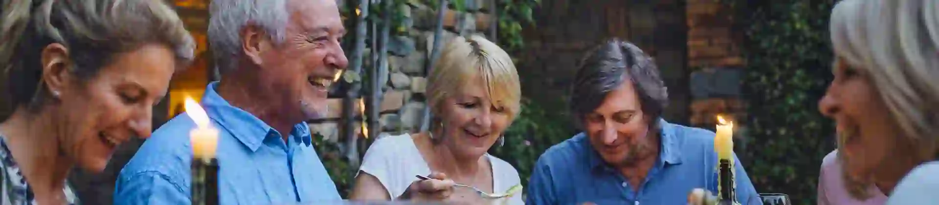 People around a table eating al fresco & sharing food by candlelight