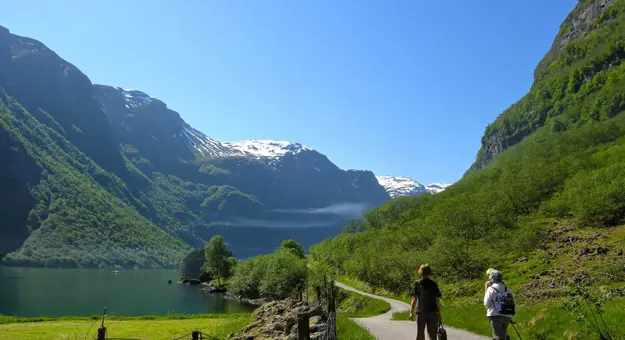 3 people hiking by The Naroyfjorden, with mountain in the distance