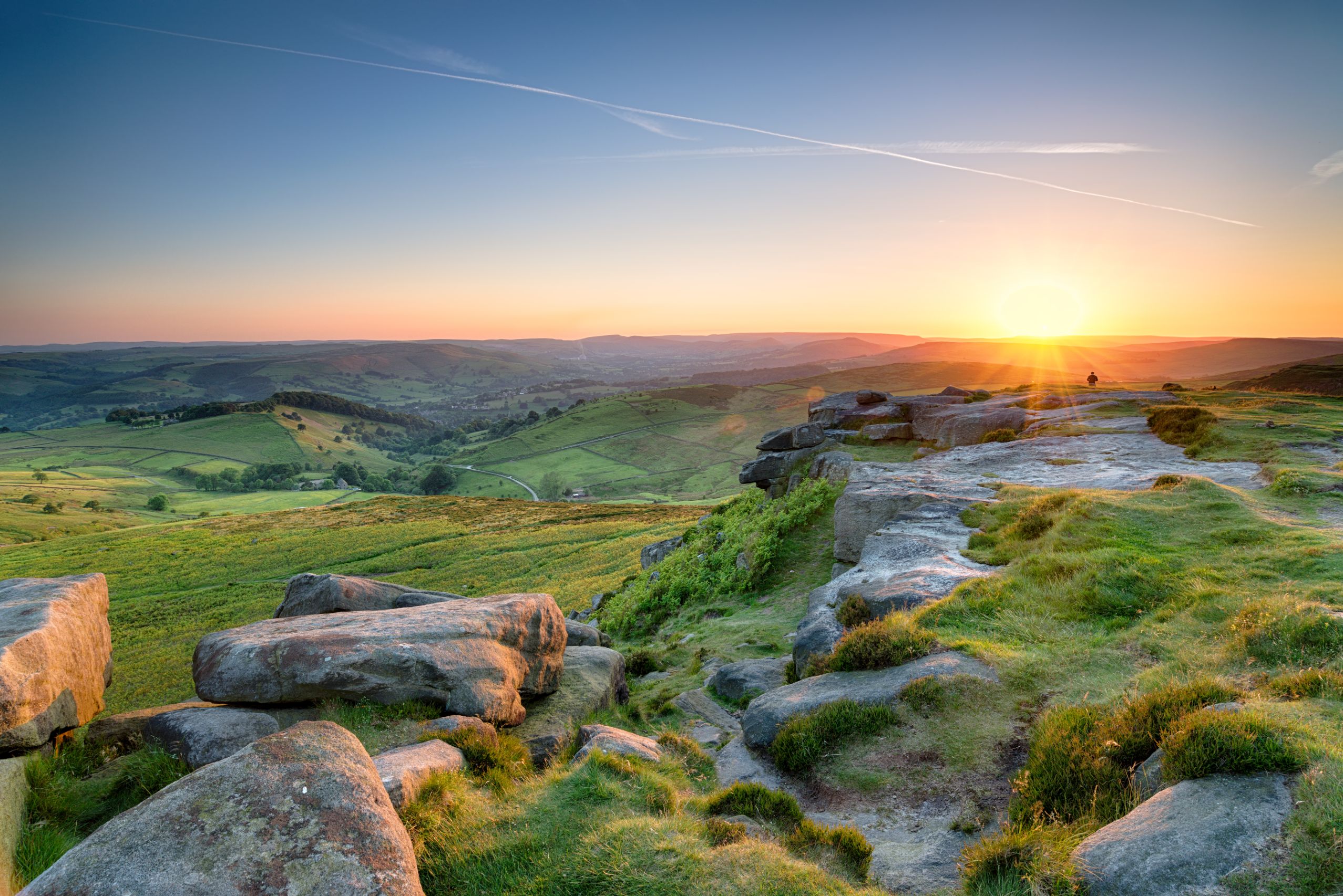 View of the Peak District at sunrise, with the sun creeping over the mountains