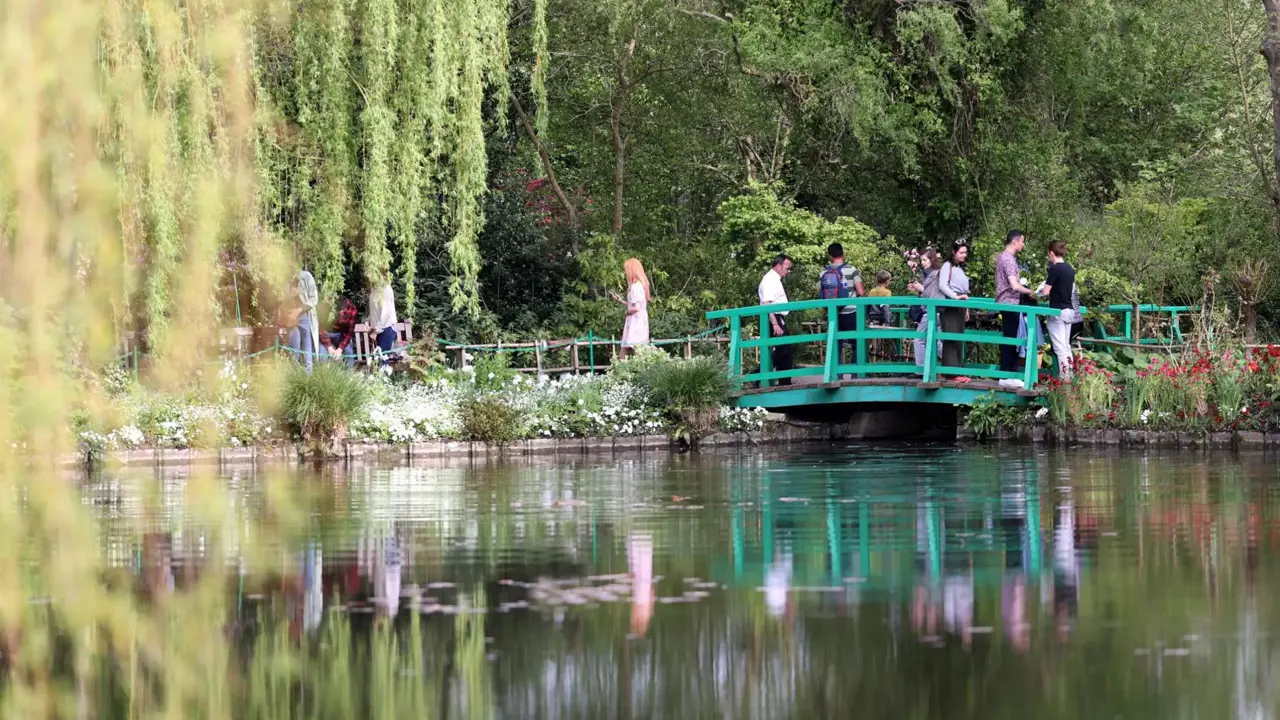 People walking over the iconic wooden bridge above the pond in Claude Monet’s gardens at Giverny