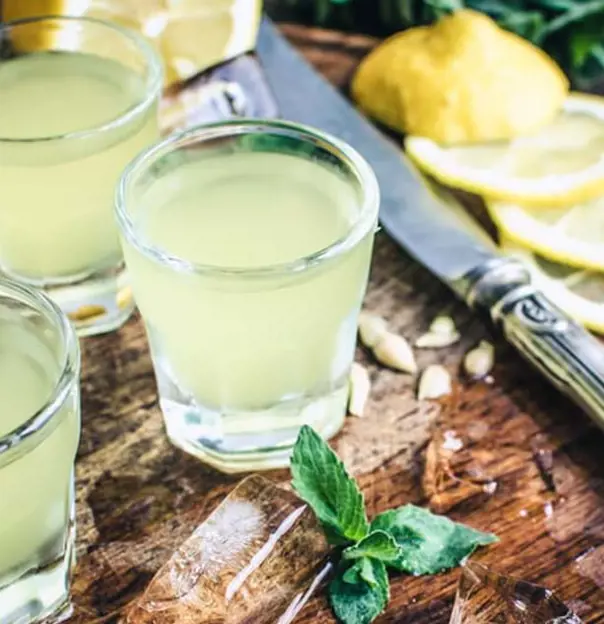 Close up of glasses of Limoncello, with lemons next to them