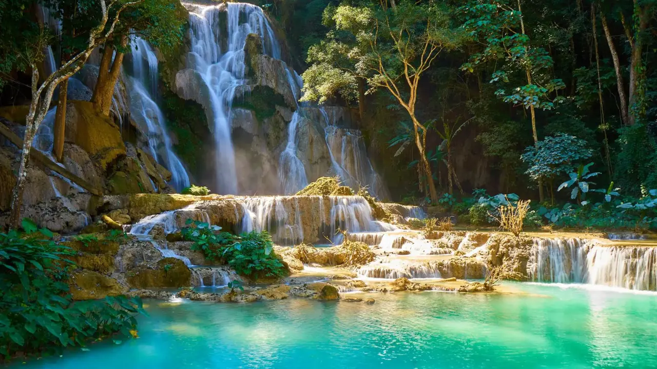 Kuang Si Falls in Laos, featuring turquoise limestone pools and cascading waterfalls framed by dense green jungle
