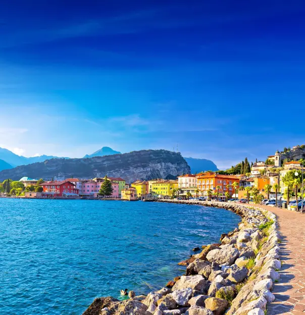 Waterfront in Torbole, Lake Garda, showing pavement and buildings and mountains in the distance