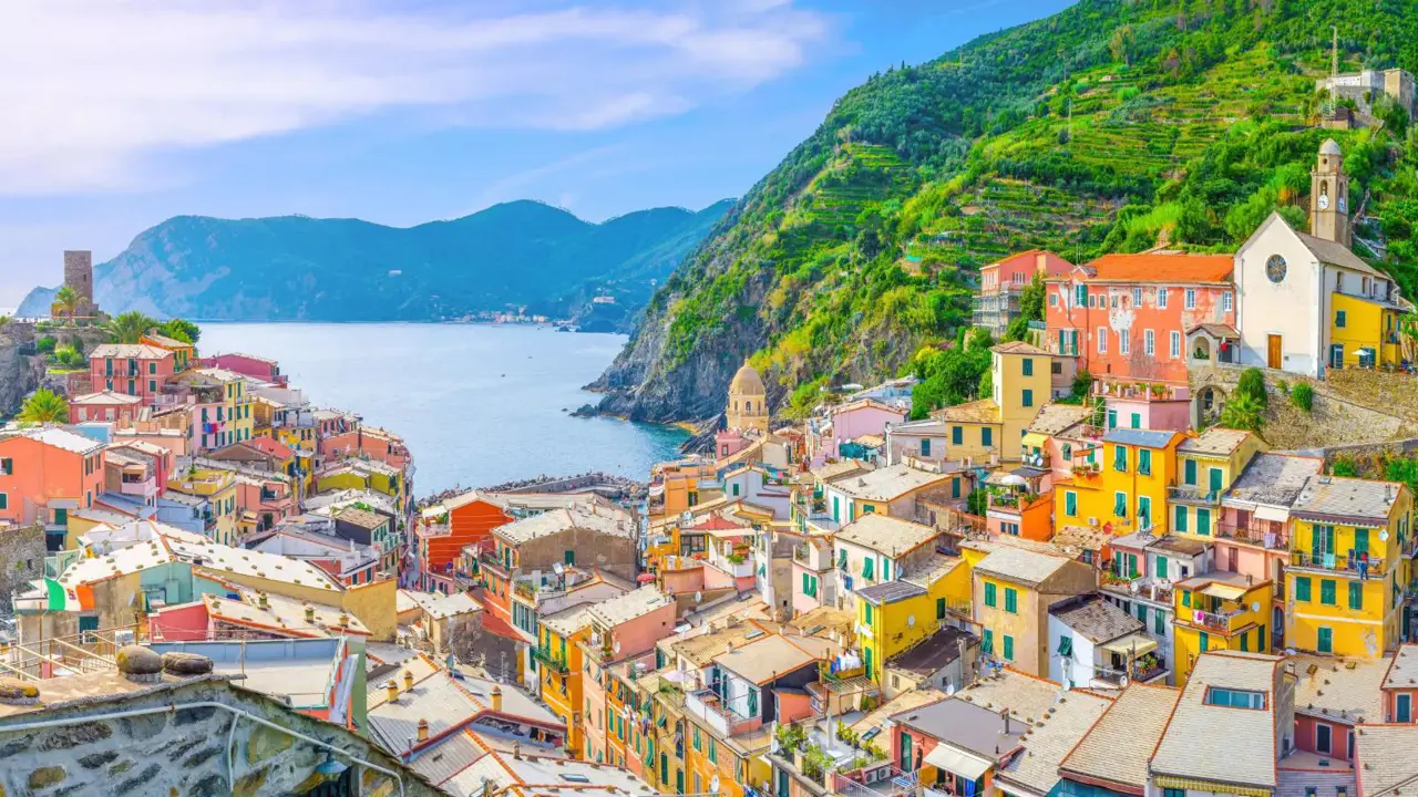 Scenic view of Vernazza, a colourful coastal village in Cinque Terre, with blue sea and a mountains in the distance