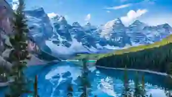 Snow-capped Rocky Mountains towering over the serene, turquoise Moraine Lake in Canada, with dense pine forests lining the shores and a clear blue sky above