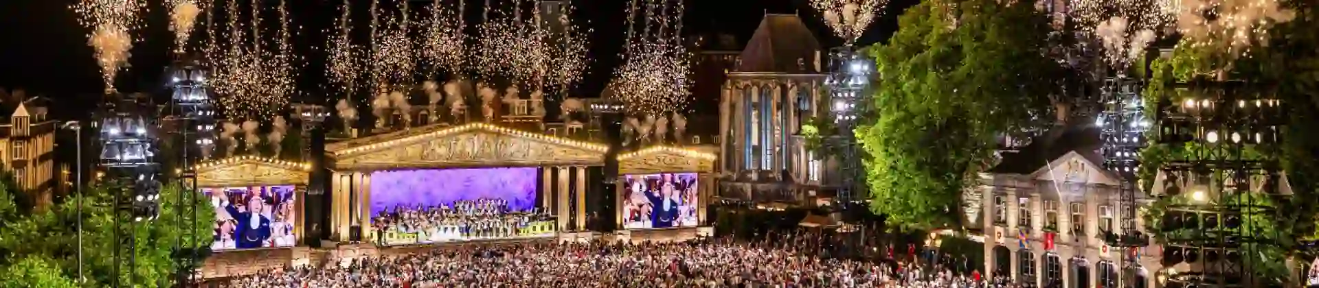 André Rieu performing live in Maastricht's Vrijthof square whilst fireworks light up the sky above the stage