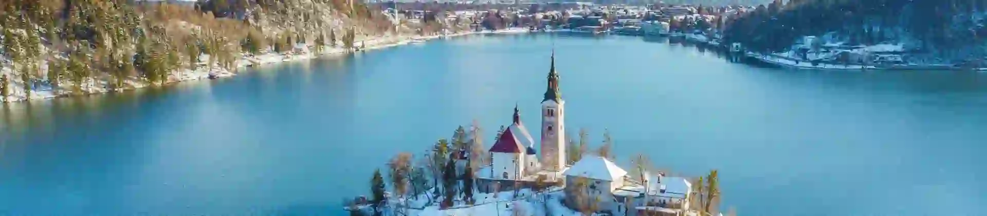 Lake Bled in winter with its island church in the centre and frosty mountains in the background