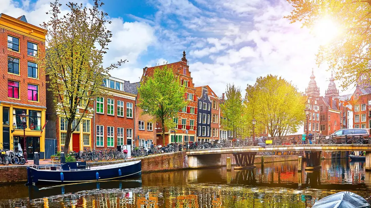Scenic view of a canal in Amsterdam, Netherlands, with traditional Dutch buildings lining both sides