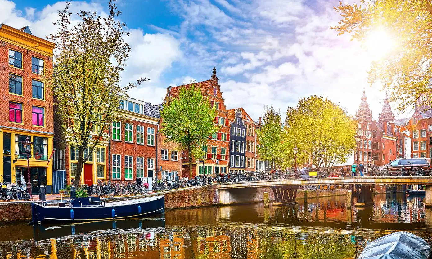 Scenic view of a canal in Amsterdam, Netherlands, with traditional Dutch buildings lining both sides