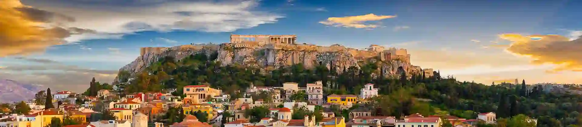 View of a city with colourful buildings and a rocky hill with ruins on the top.