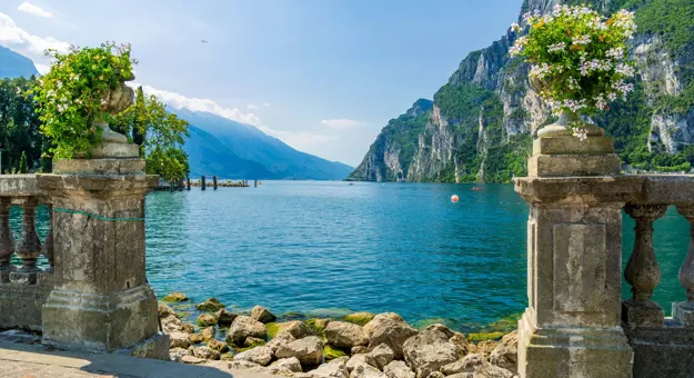 View of Riva Del Garda with bouquets of flowers in the forefront and mountains in the distance