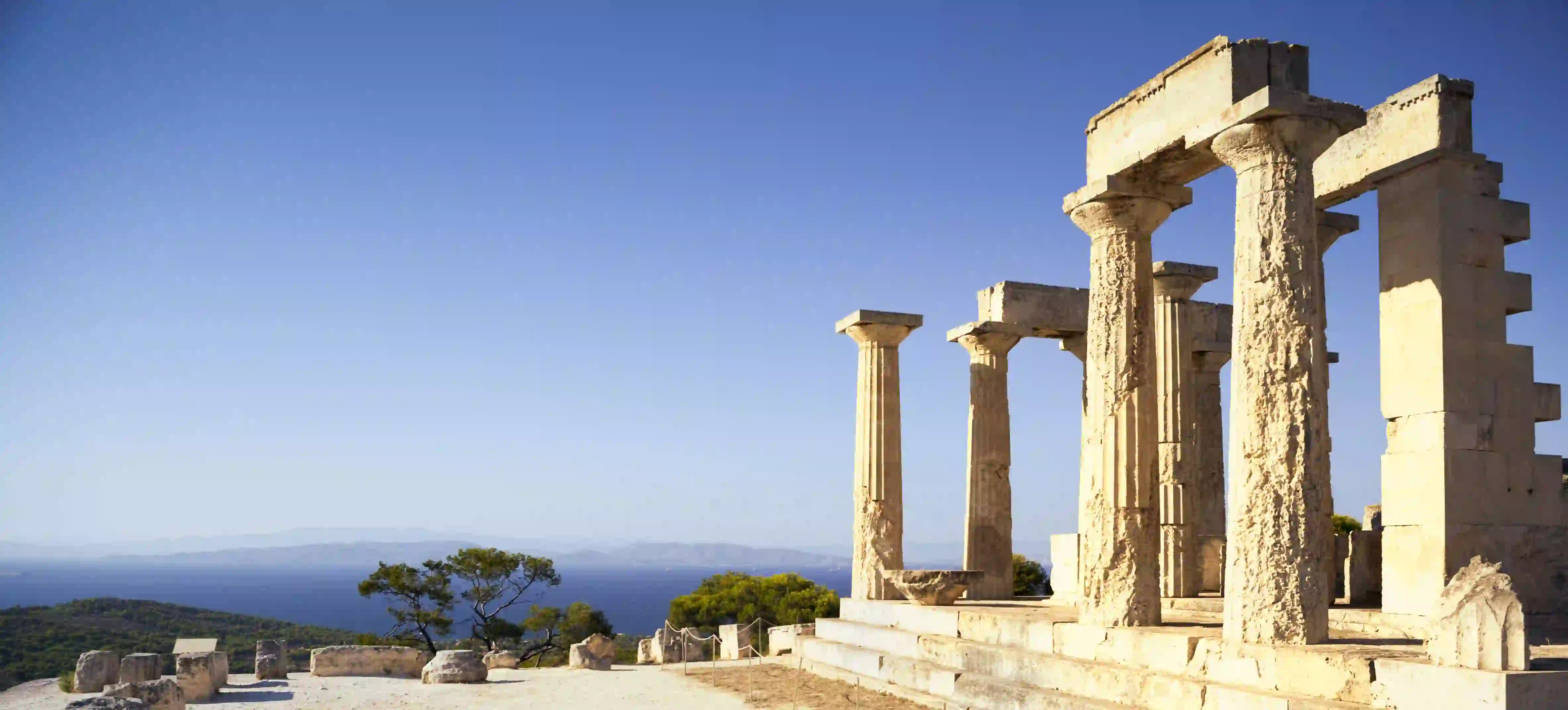 Ruins of a temple on a hill, with view of mountains in the distance